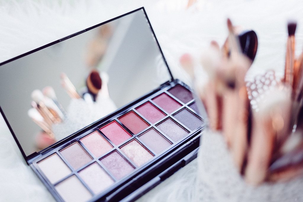 Eyeshadow palette and makeup brushes on a soft white background